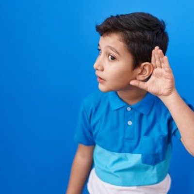 Young boy with his left hand cupped to his left ear.